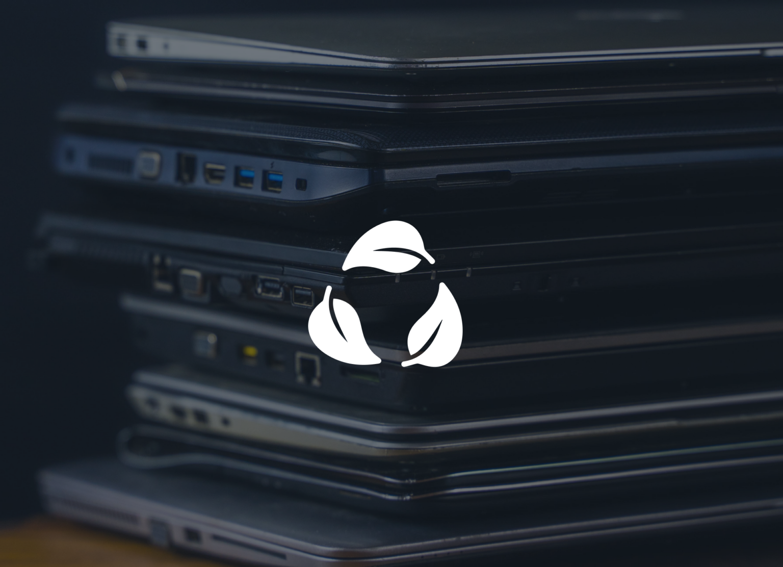 Tre vita löv i en cirkelform för att symbolisera hållbarhet och i bakgrunden synd flera ihopfällda laptops i olika utföranden