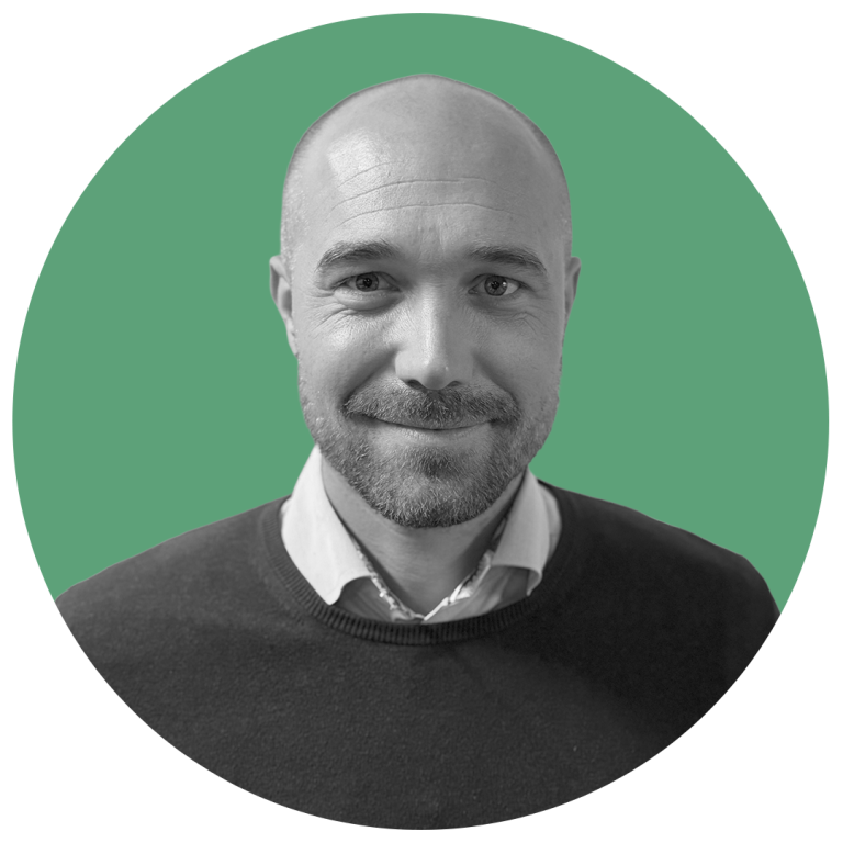 Svartvit profilbild med grön bakgrund på en man med svart tröja och vit skjorta med namn Niclas Apelgren med arbetstitel sales manager